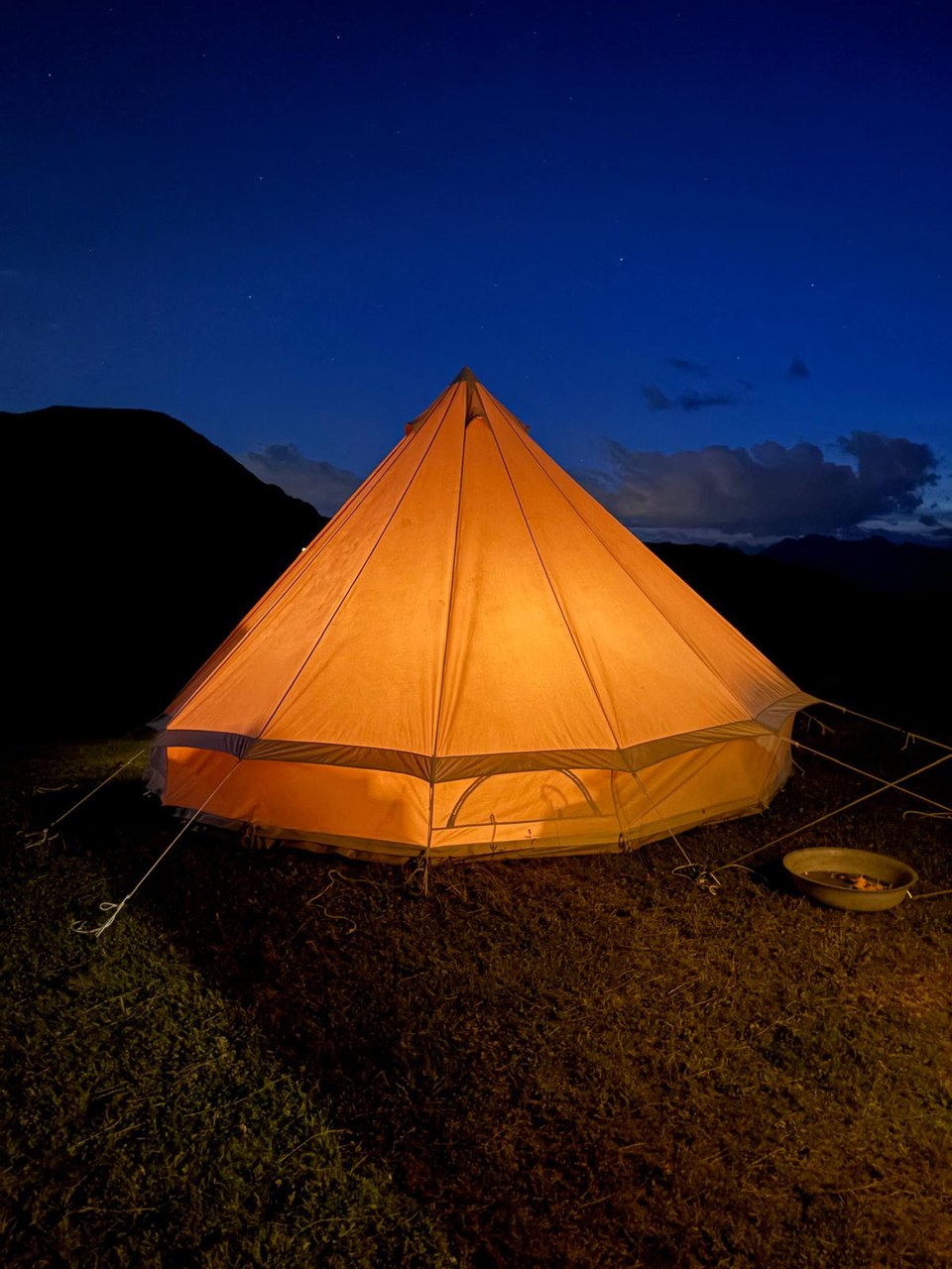 Ein von innen beleuchtetes Glamping-Zelt auf der Alm unter dem Sternenhimmel