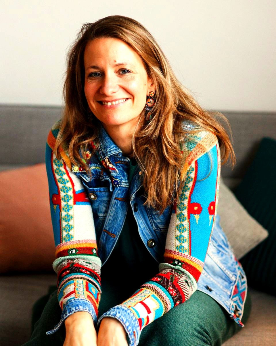 Stephanie Wille sitzt auf einem Sofa und lächelt in die Kamera